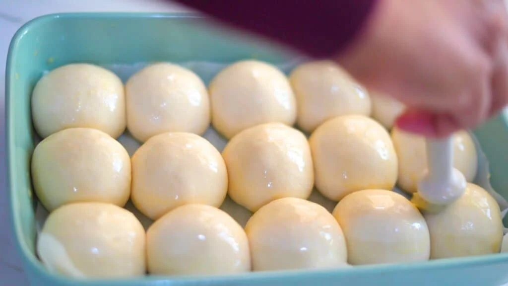 applying eggwash on sourdough dinner rolls