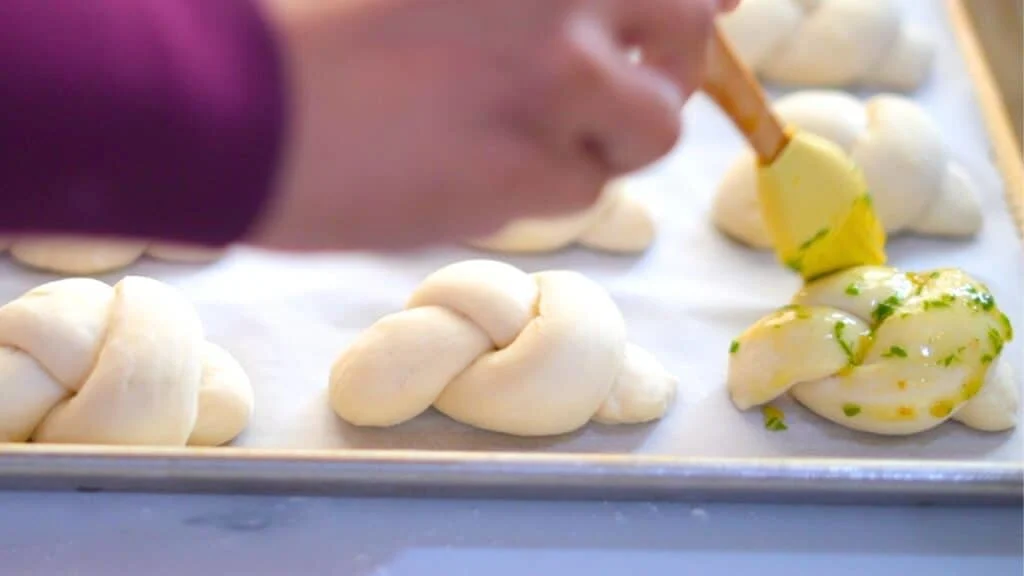 brushing garlic butter on garlic knots